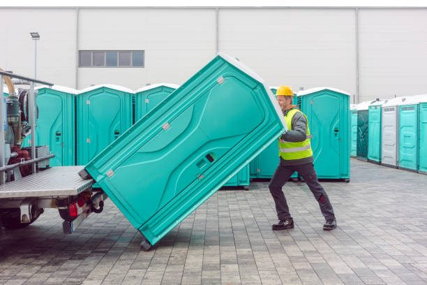 Crew member positioning a portable restroom unit on delivery